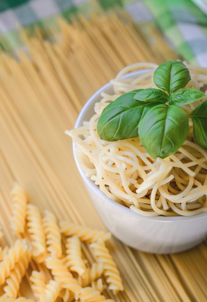 Bowl of freshly cooked spaghetti topped with basil leaves, perfect for a tasty Italian meal.